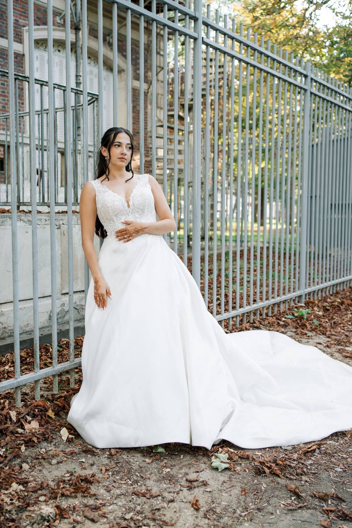Mariée et sa longue traîne près d’une grille