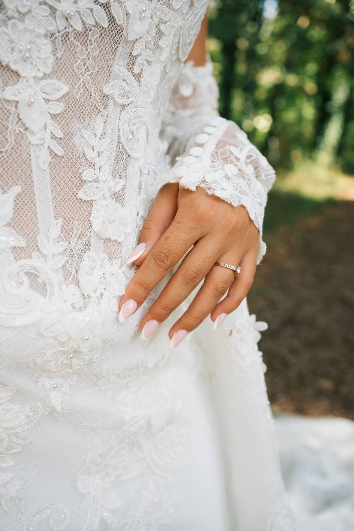 Main de la mariée et sa bague sur la dentelle de la robe